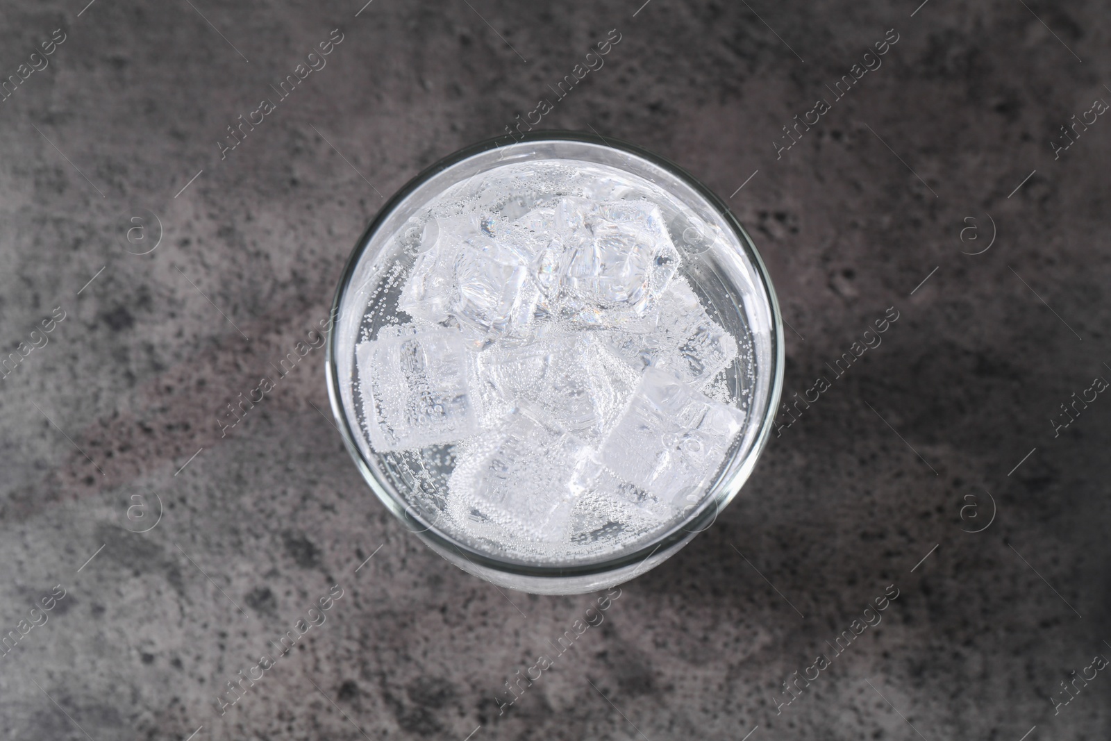 Photo of Refreshing soda water with ice cubes in glass on grey table, top view