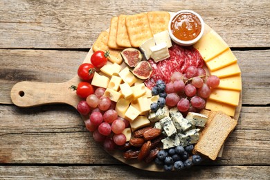 Photo of Different types of delicious cheese and other snacks on wooden table, top view