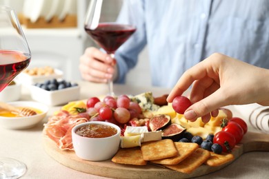 Photo of Women enjoying different snacks and wine during brunch at light grey table indoors, closeup