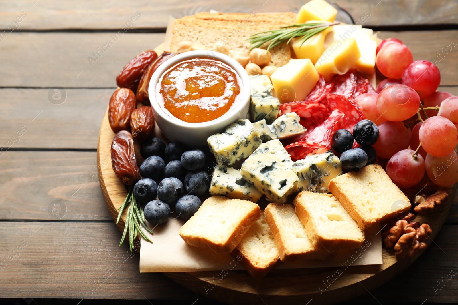 Photo of Different types of delicious cheese and other snacks on wooden table, closeup. Space for text