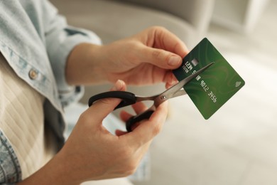 Photo of Woman cutting plastic credit card indoors, closeup