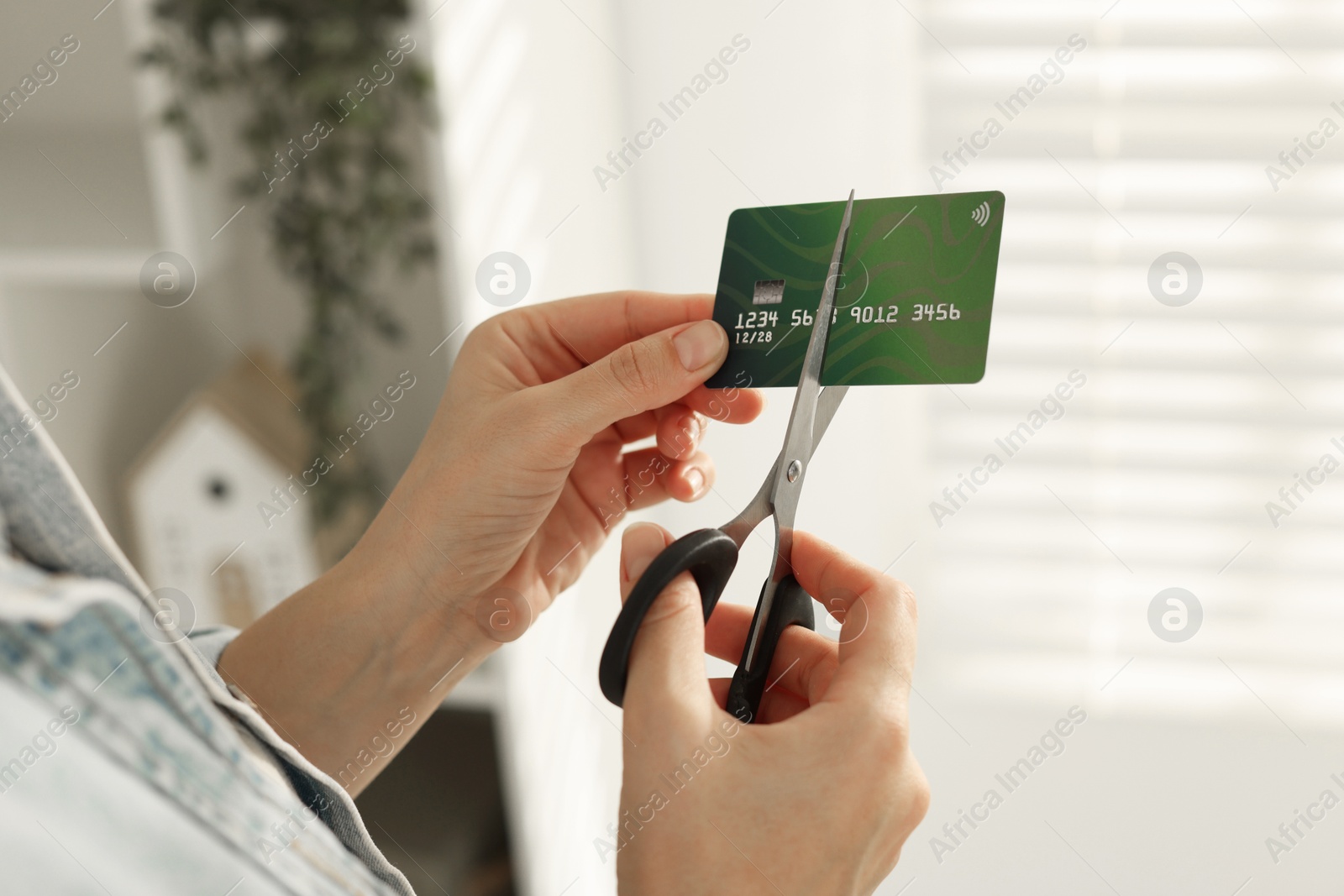 Photo of Woman cutting plastic credit card indoors, closeup