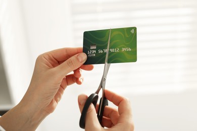 Photo of Woman cutting plastic credit card indoors, closeup