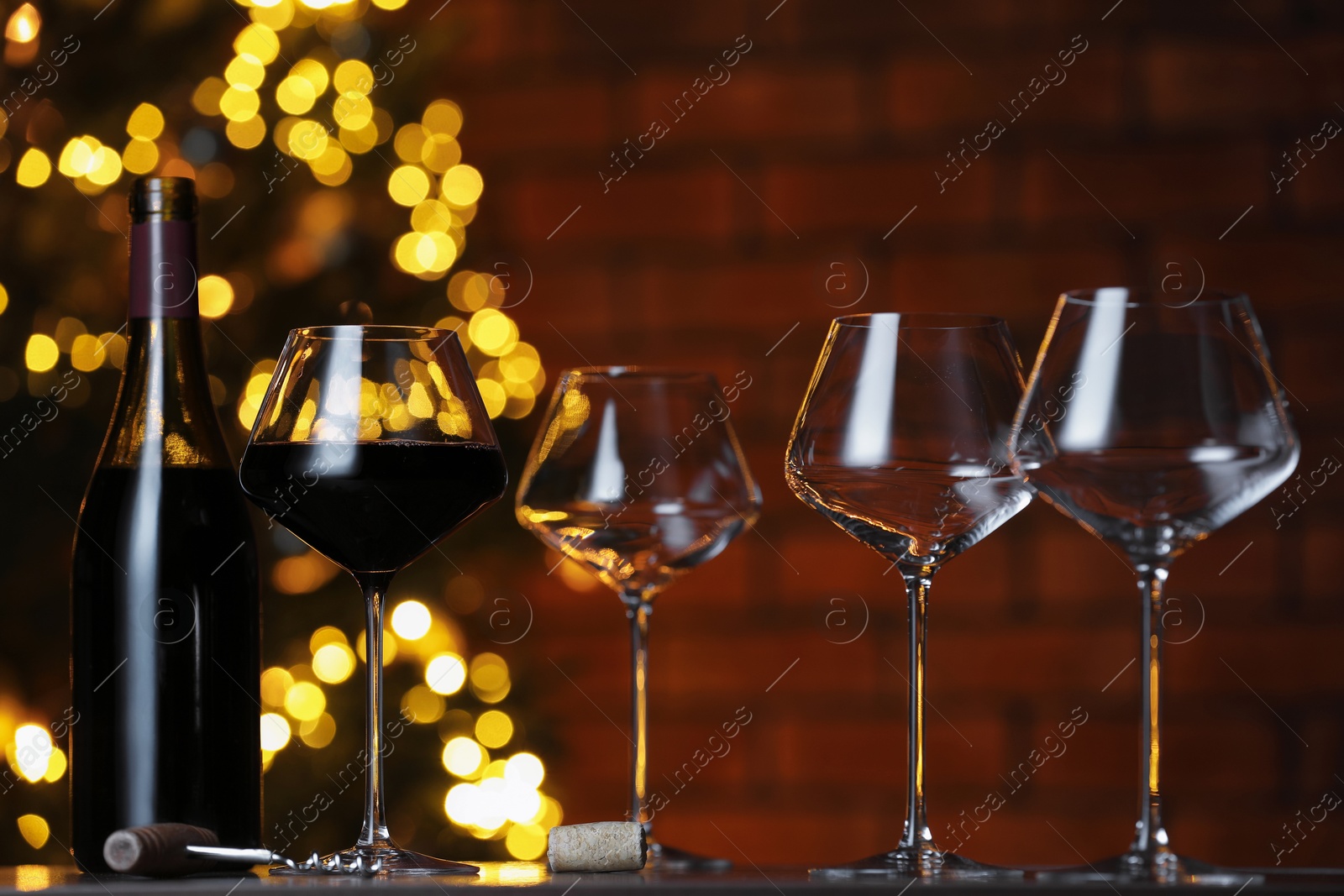 Photo of Glass with red wine and empty ones on table against blurred lights. Bokeh effect