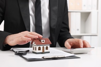 Photo of Real estate agent calculating price for house at white table in office, closeup. Home appraisal