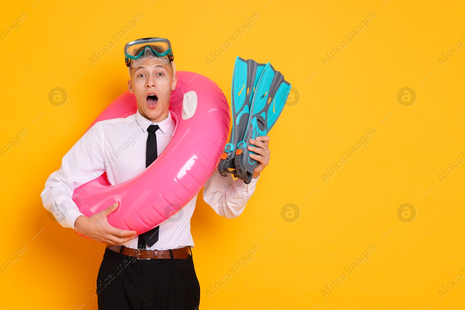 Photo of Businessman with inflatable ring, flippers and diving mask on orange background, space for text