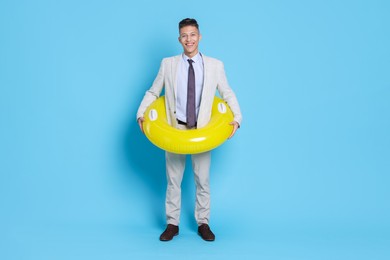 Businessman with inflatable ring on light blue background