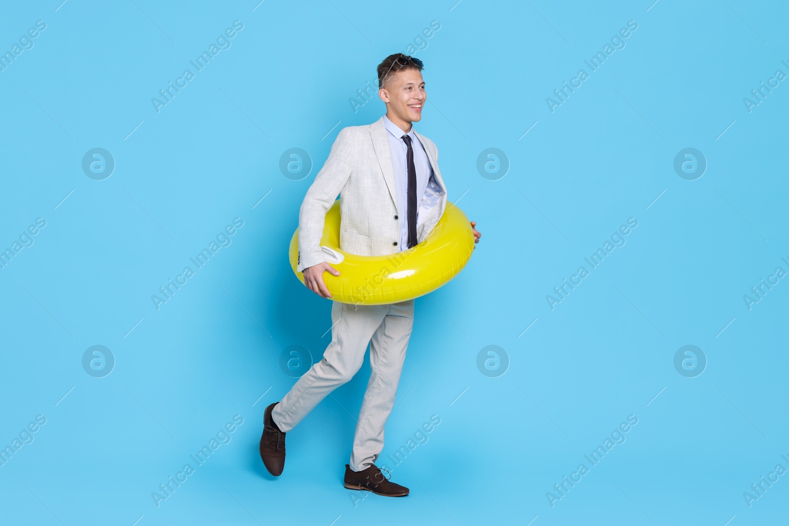 Photo of Businessman with inflatable ring on light blue background