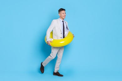 Businessman with inflatable ring on light blue background