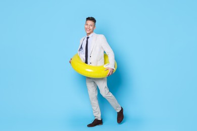 Photo of Businessman with inflatable ring on light blue background