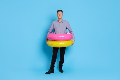 Photo of Businessman with inflatable rings on light blue background