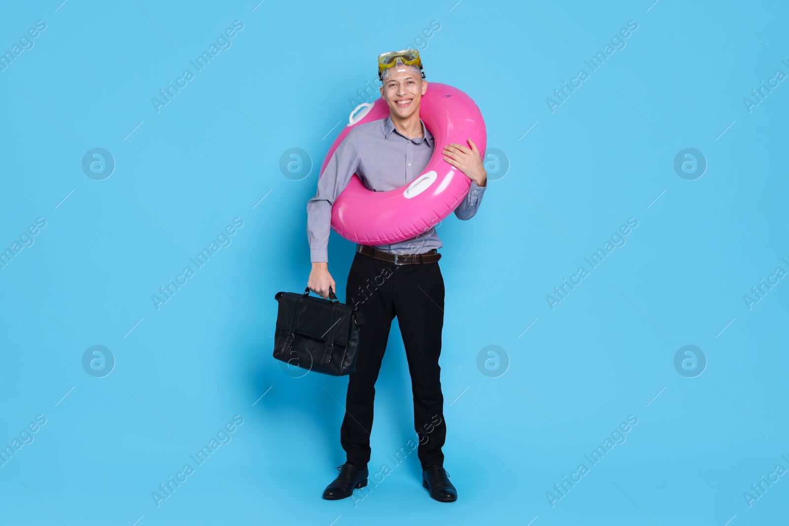 Photo of Businessman with inflatable ring, briefcase and diving mask on light blue background