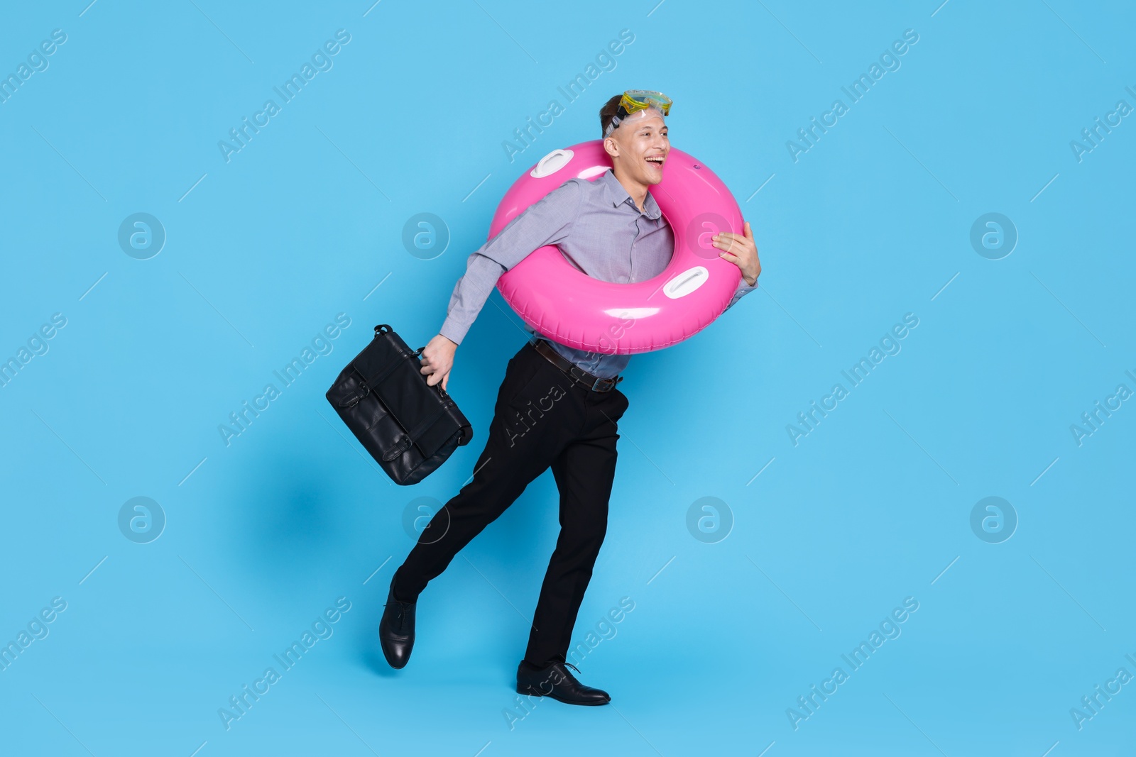 Photo of Businessman with inflatable ring, briefcase and diving mask on light blue background