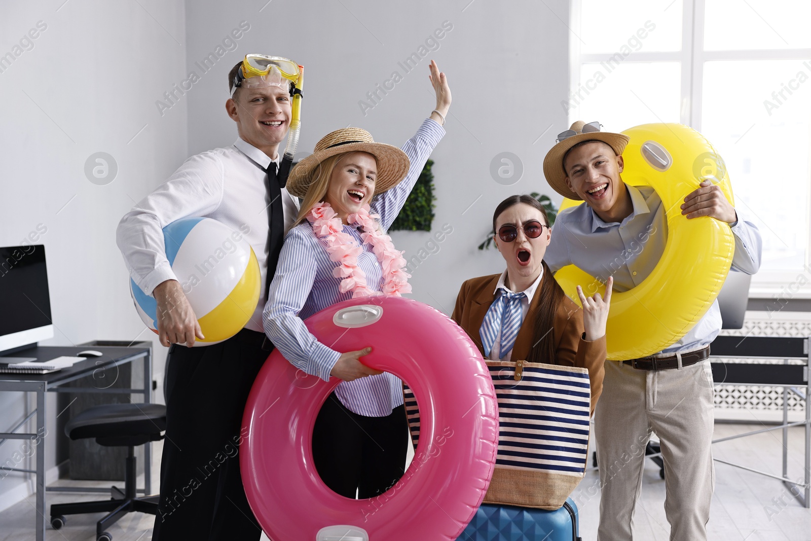 Photo of Colleagues with different beach accessories having fun in office