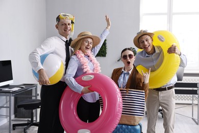 Photo of Colleagues with different beach accessories having fun in office