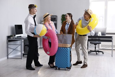 Photo of Colleagues with different beach accessories having fun in office