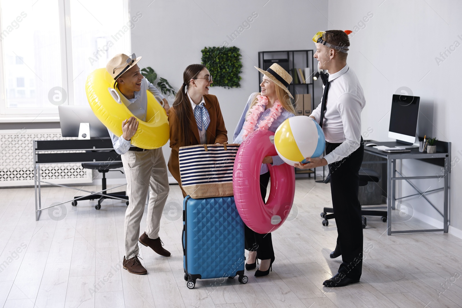 Photo of Colleagues with different beach accessories having fun in office