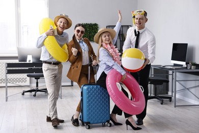 Colleagues with different beach accessories having fun in office