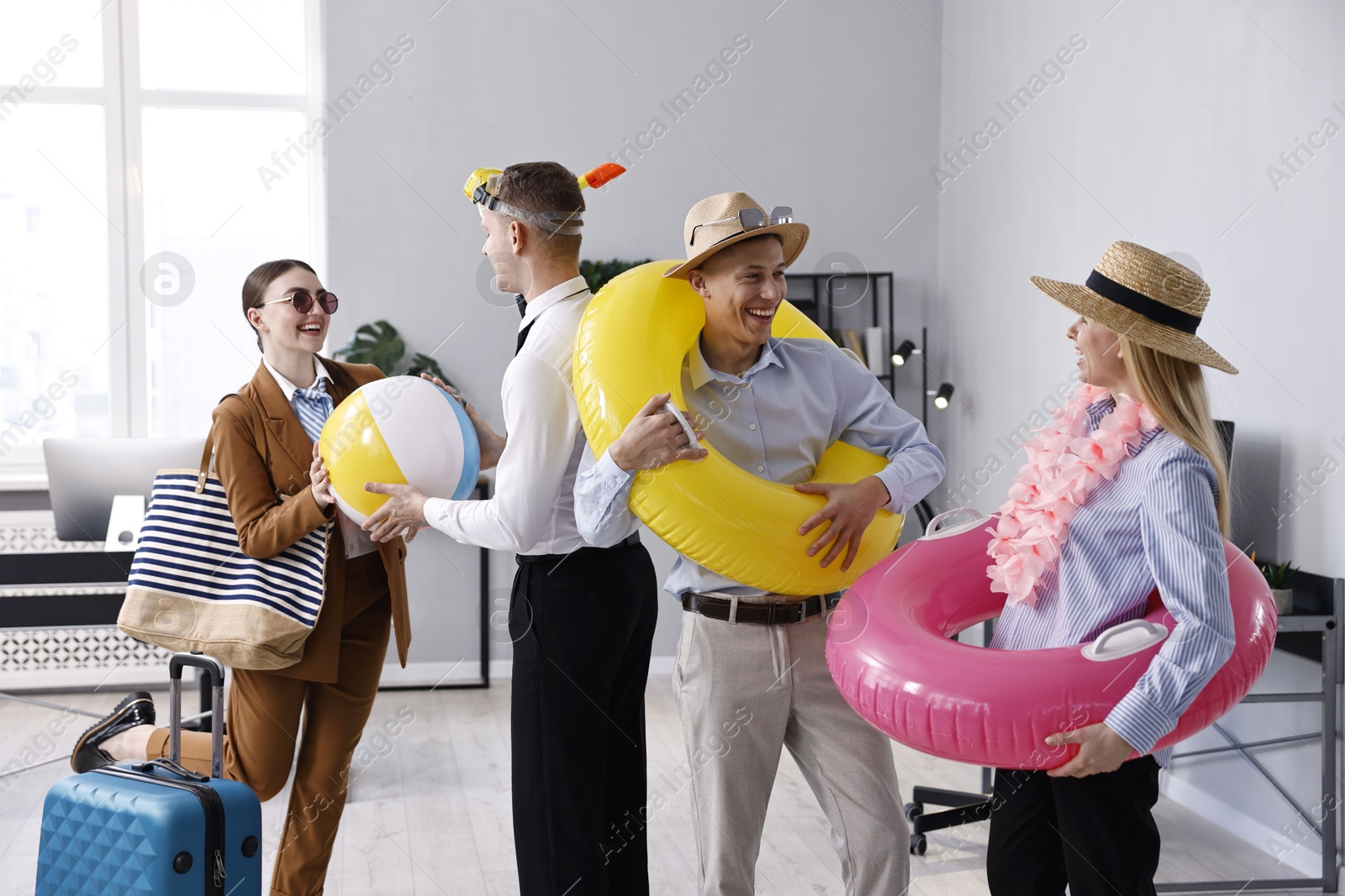 Photo of Colleagues with different beach accessories having fun in office