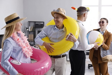 Photo of Colleagues with different beach accessories having fun in office