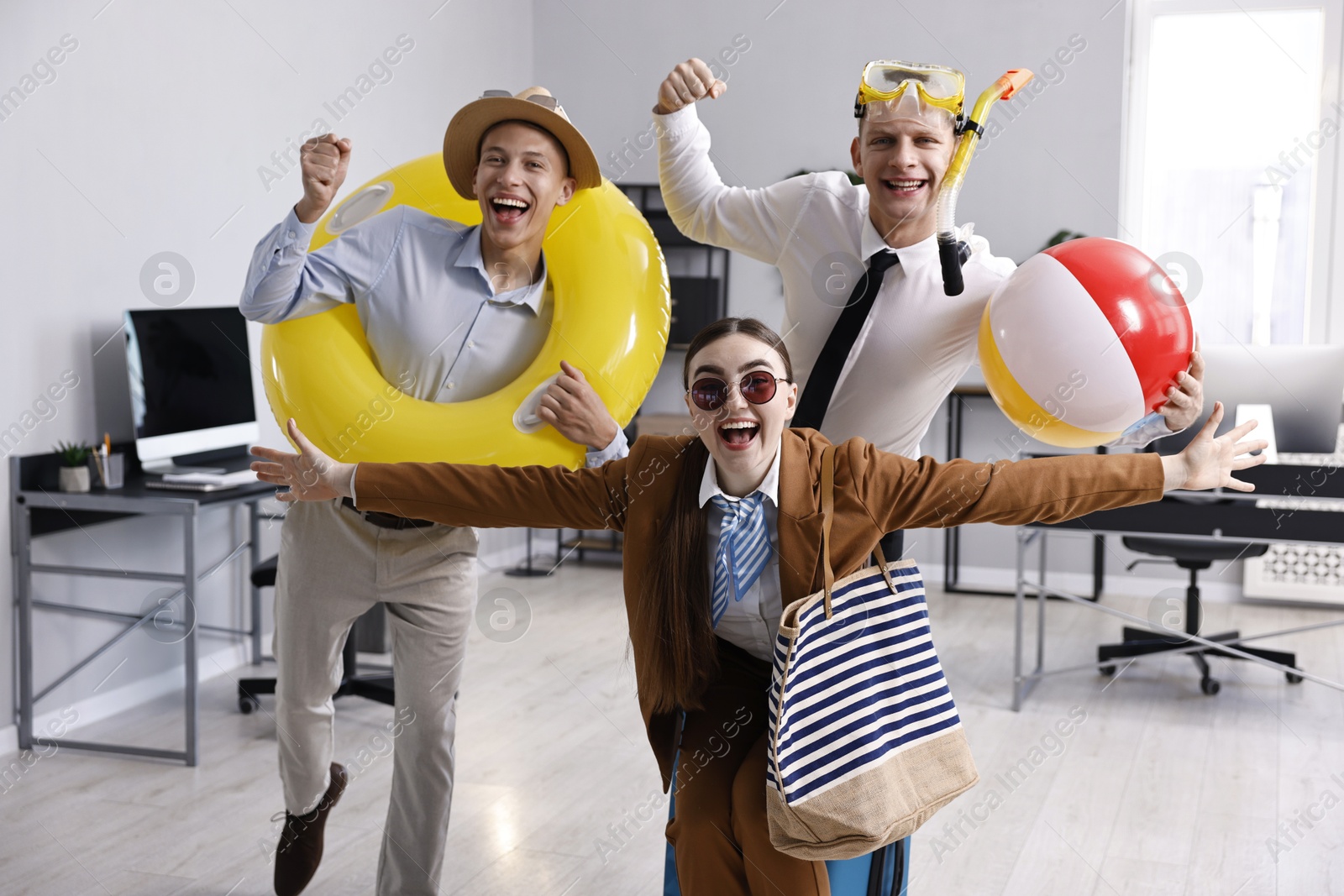 Photo of Colleagues with different beach accessories having fun in office