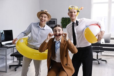 Photo of Colleagues with different beach accessories having fun in office