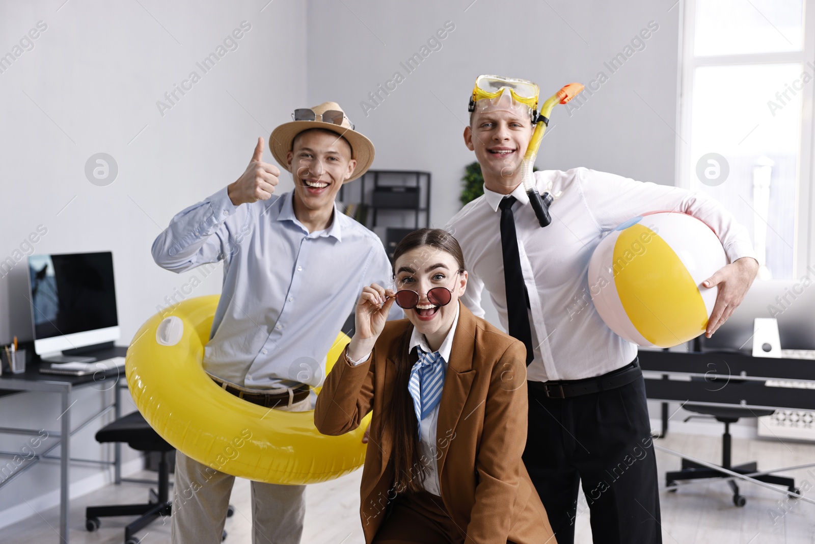 Photo of Colleagues with different beach accessories having fun in office