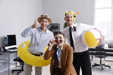 Photo of Colleagues with different beach accessories having fun in office