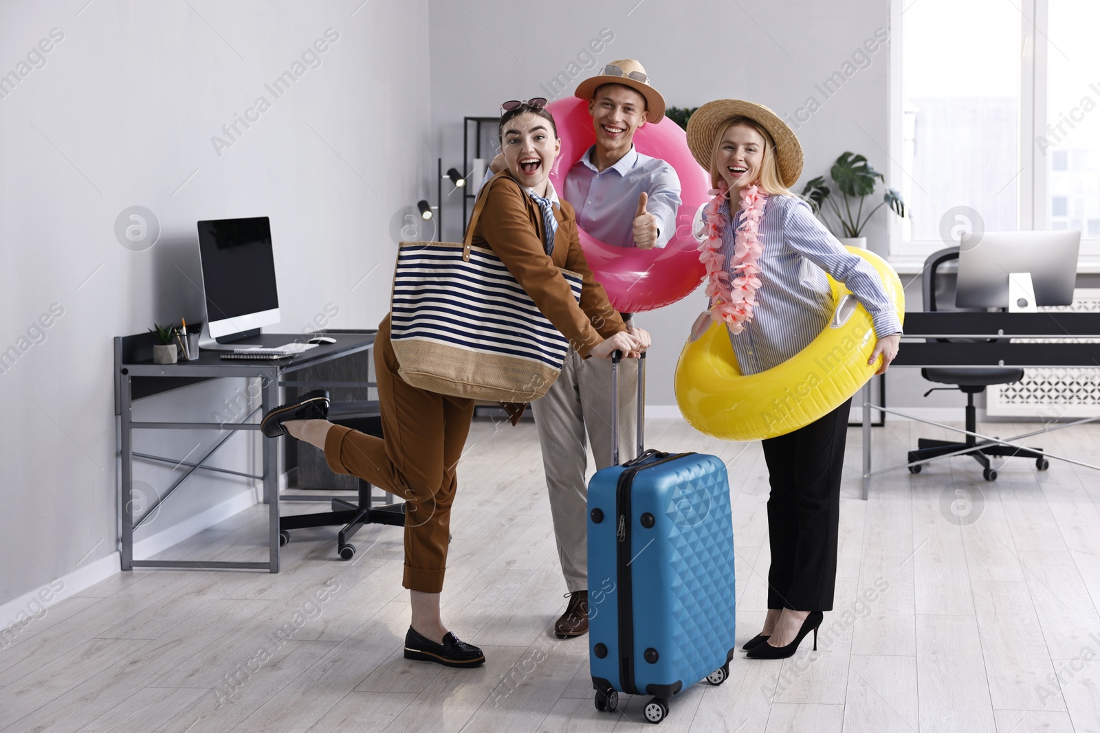 Photo of Colleagues with different beach accessories having fun in office