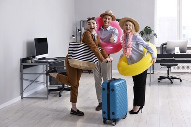 Photo of Colleagues with different beach accessories having fun in office