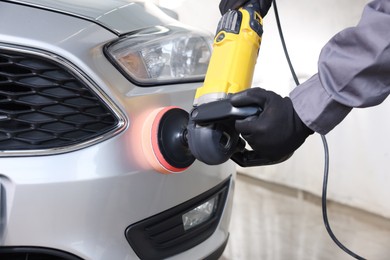 Photo of Man polishing car with orbital polisher indoors, closeup