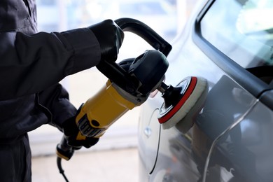 Photo of Man polishing car with orbital polisher indoors, closeup