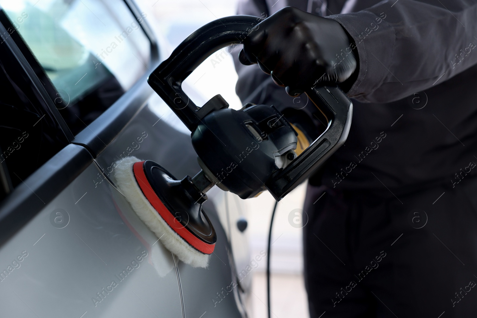 Photo of Man polishing car with orbital polisher indoors, closeup