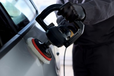 Photo of Man polishing car with orbital polisher indoors, closeup