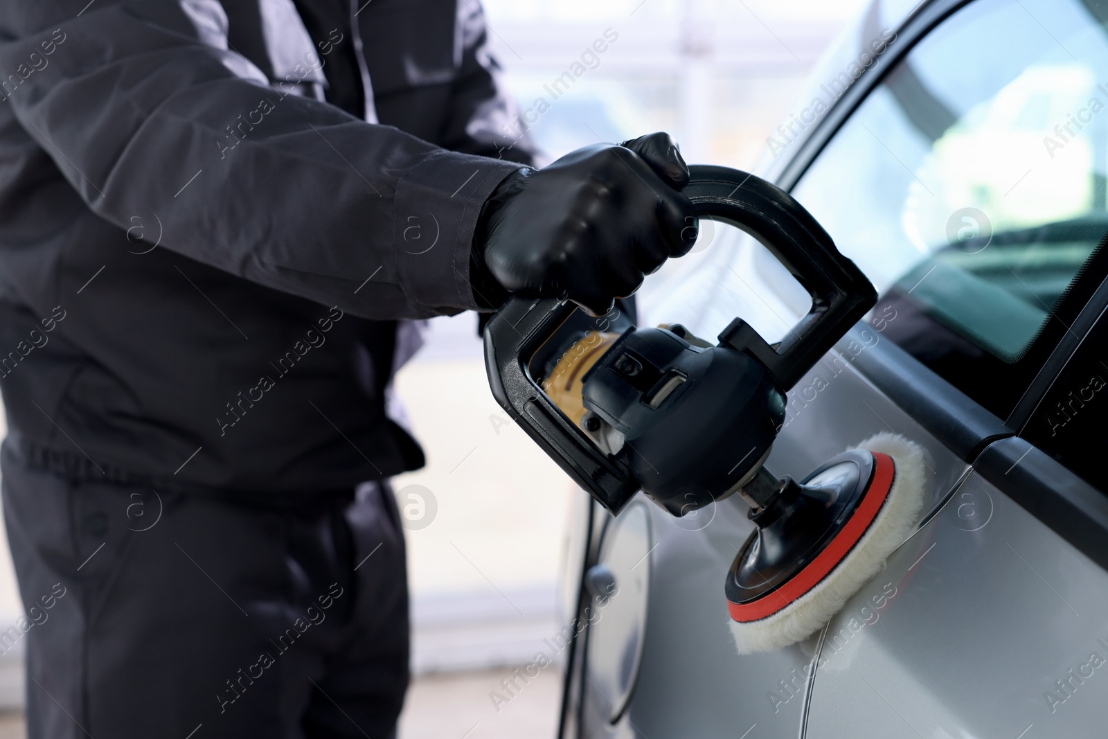 Photo of Man polishing car with orbital polisher indoors, closeup