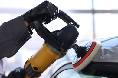 Photo of Man polishing car with orbital polisher indoors, closeup