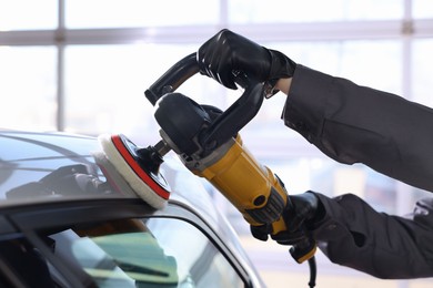 Photo of Man polishing car with orbital polisher indoors, closeup