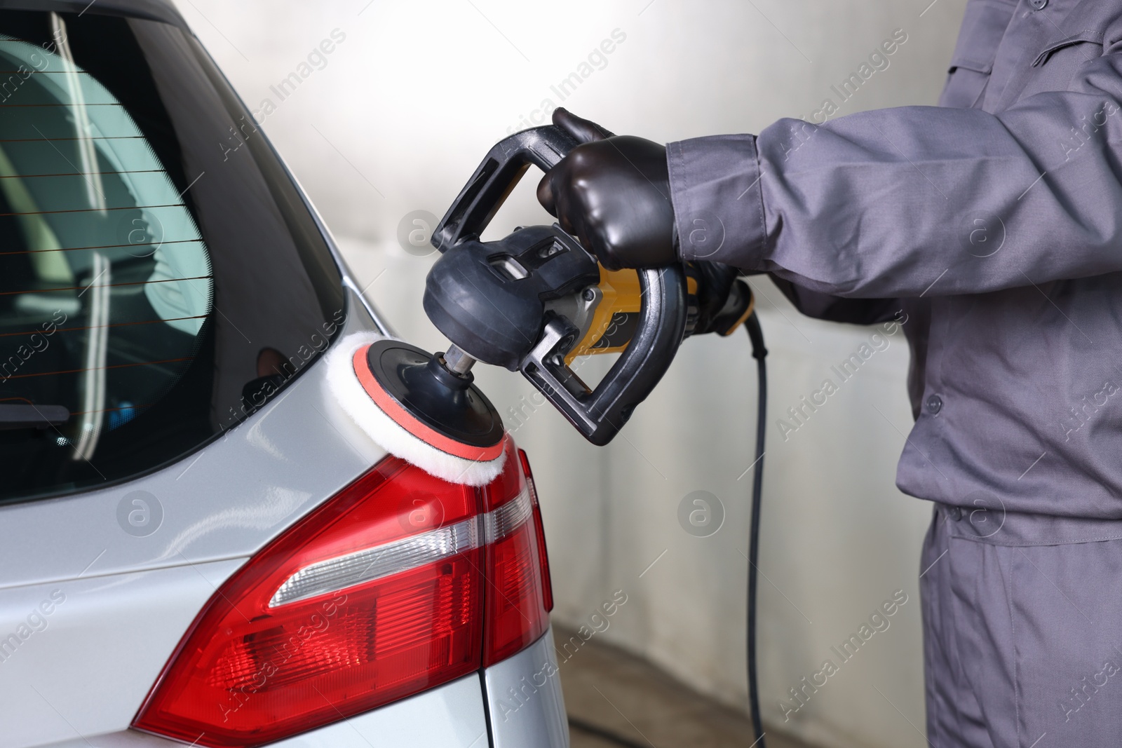 Photo of Man polishing car with orbital polisher indoors, closeup