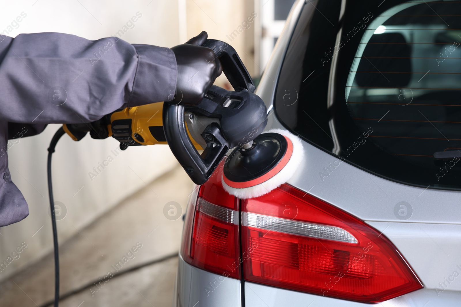 Photo of Man polishing car with orbital polisher indoors, closeup