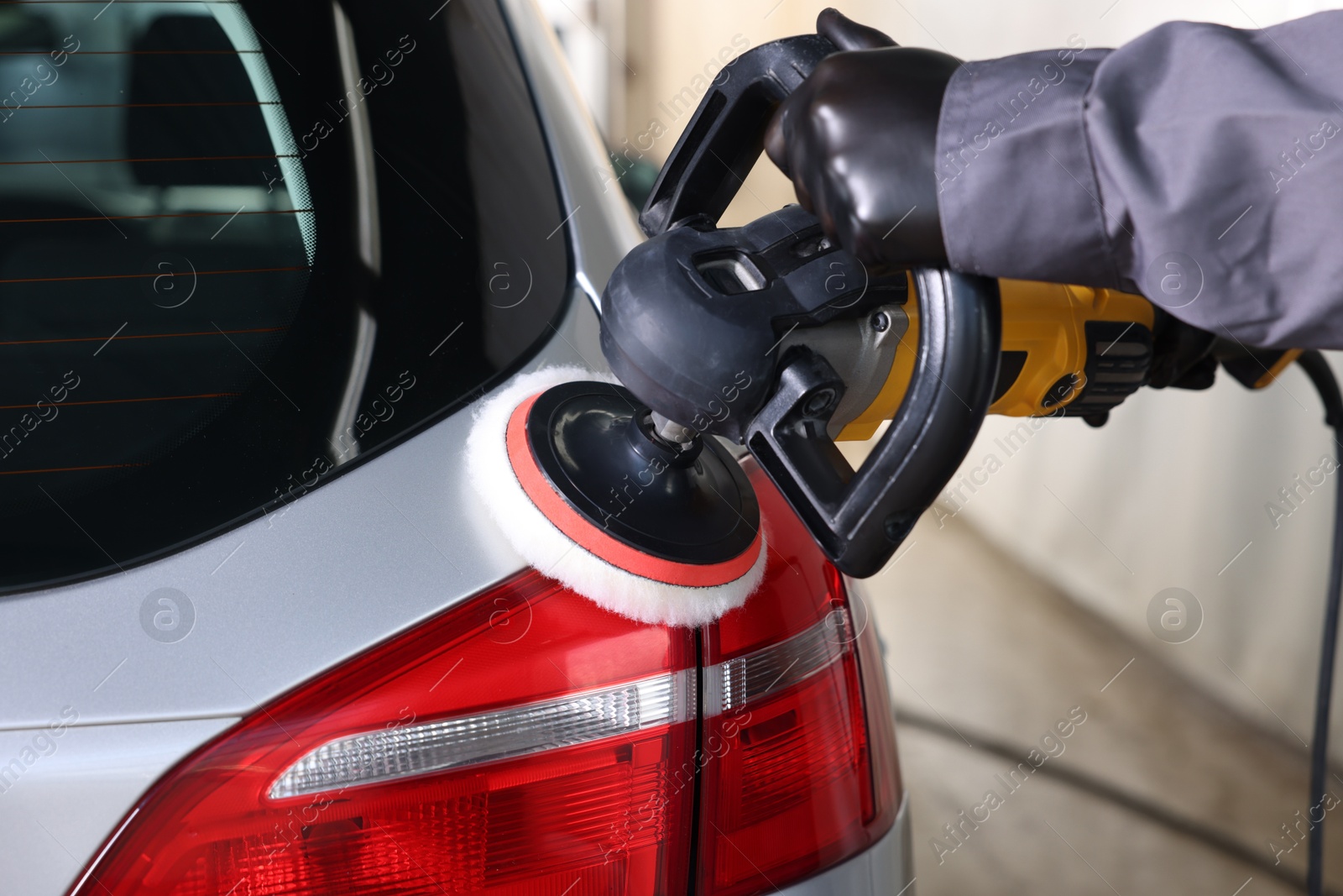 Photo of Man polishing car with orbital polisher indoors, closeup