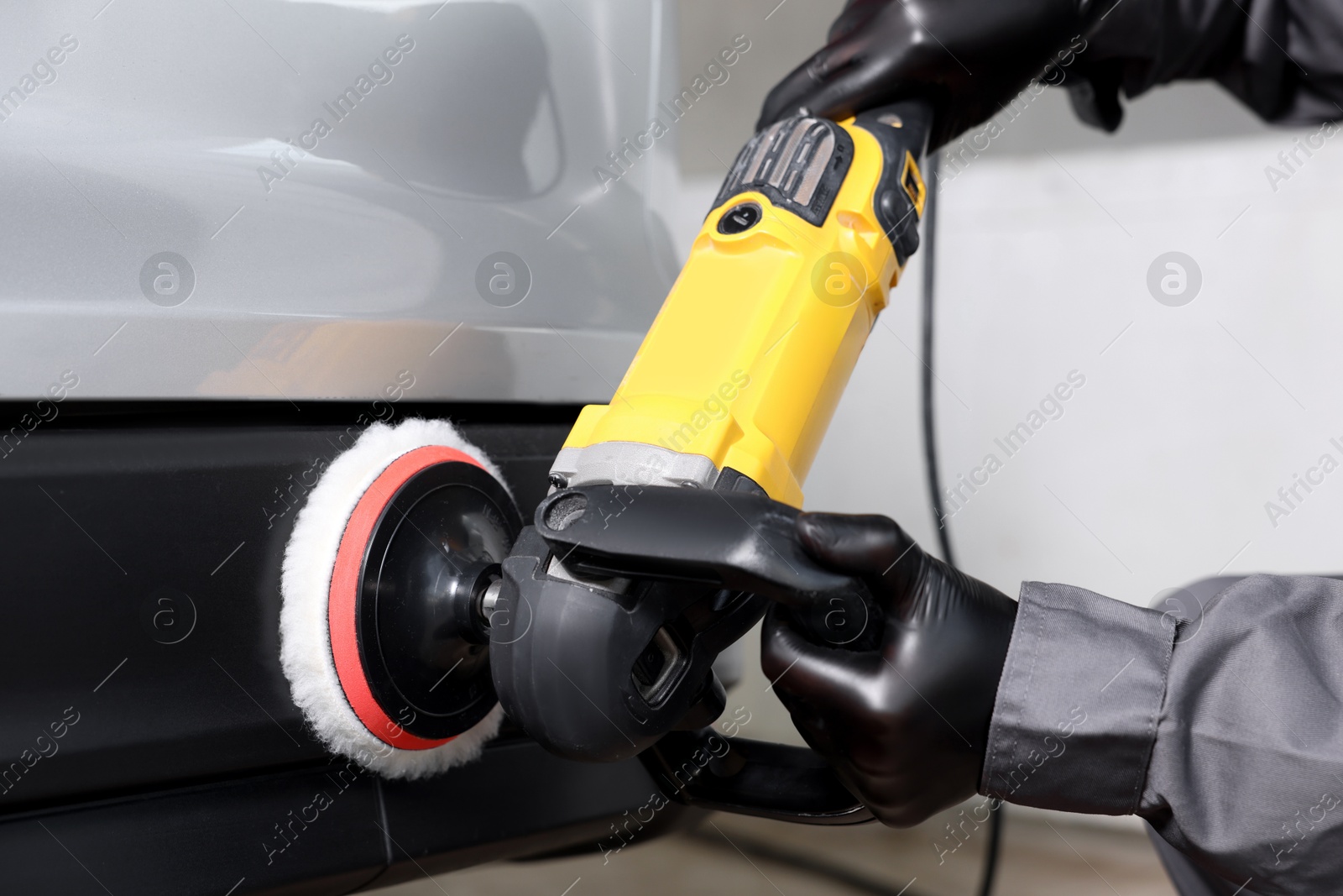 Photo of Man polishing car with orbital polisher indoors, closeup