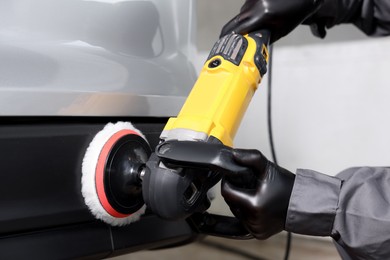 Photo of Man polishing car with orbital polisher indoors, closeup