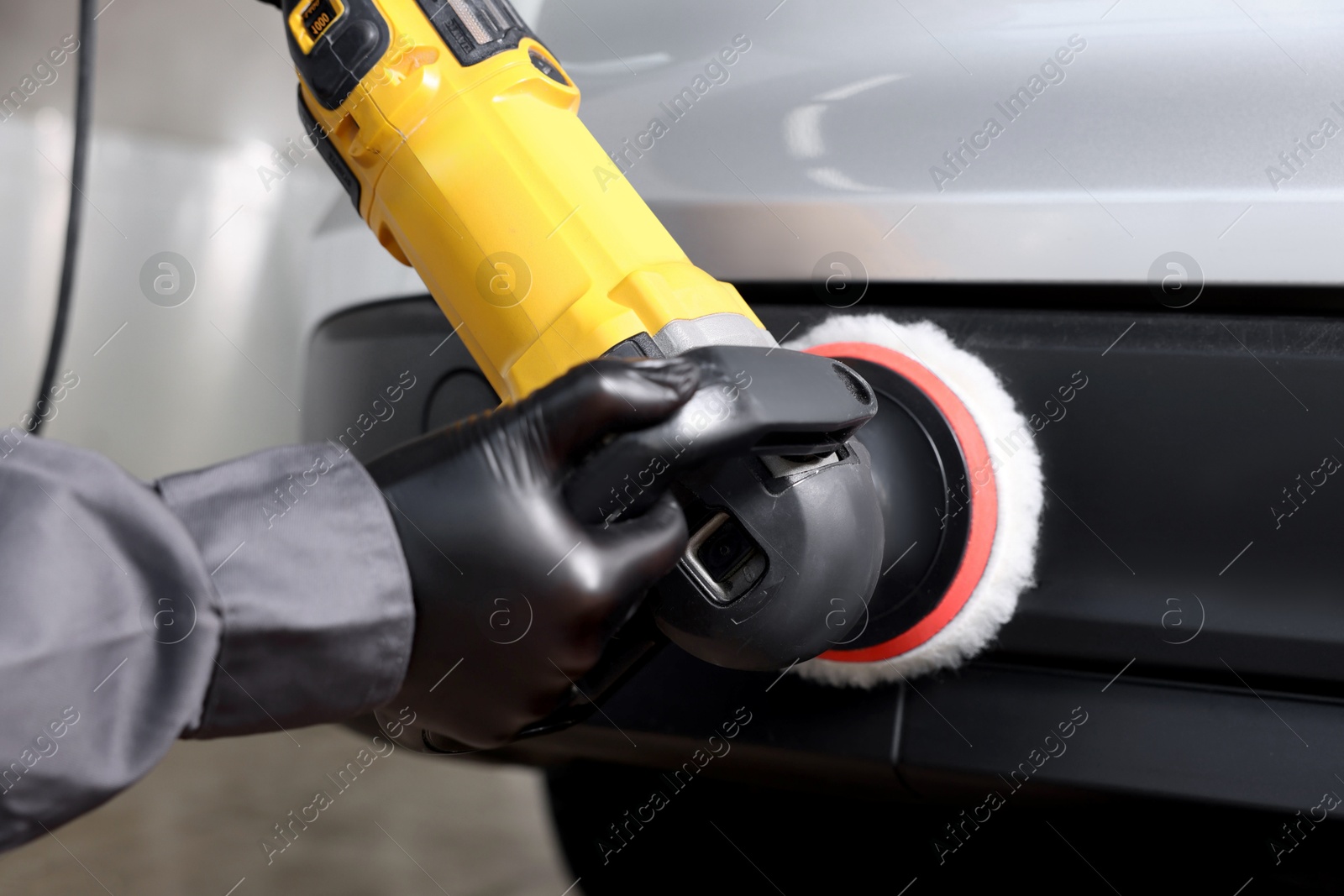 Photo of Man polishing car with orbital polisher indoors, closeup