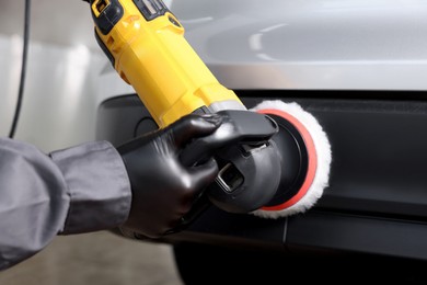 Photo of Man polishing car with orbital polisher indoors, closeup