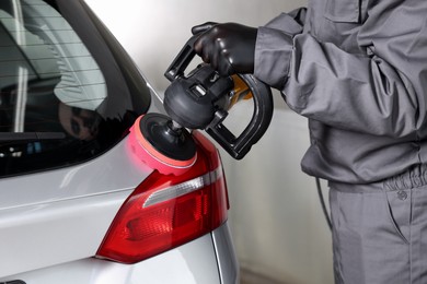 Photo of Man polishing car rear light with orbital polisher indoors, closeup