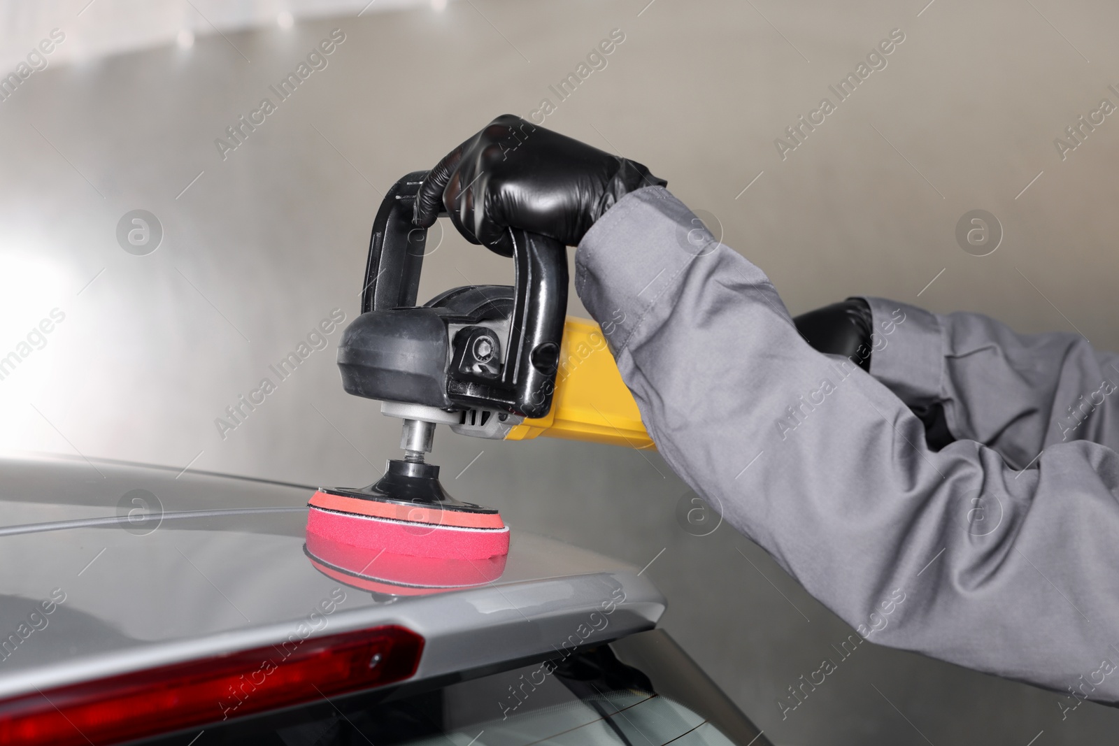 Photo of Man polishing car with orbital polisher indoors, closeup