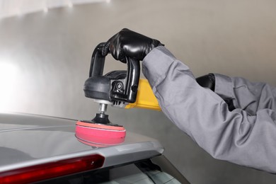 Photo of Man polishing car with orbital polisher indoors, closeup