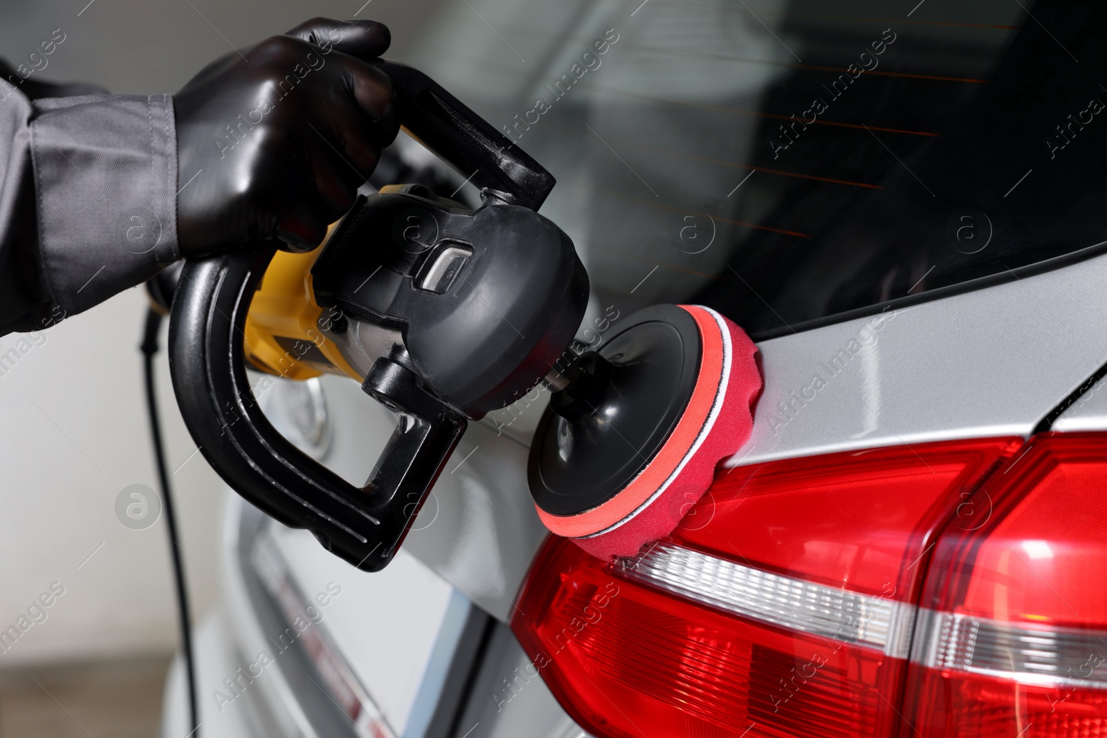 Photo of Man polishing car with orbital polisher indoors, closeup