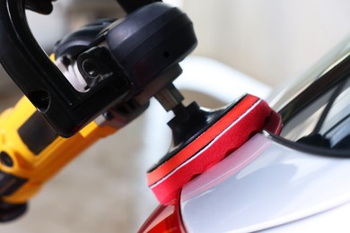 Photo of Man polishing car with orbital polisher indoors, closeup