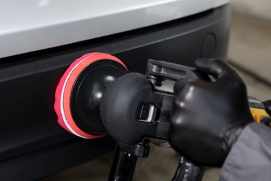 Photo of Man polishing car with orbital polisher indoors, closeup